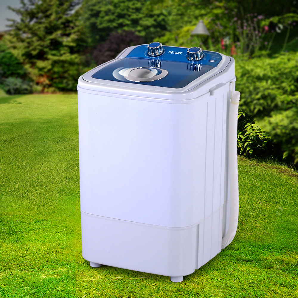 Washing machine placed on grass outdoors, angled view highlighting portability.