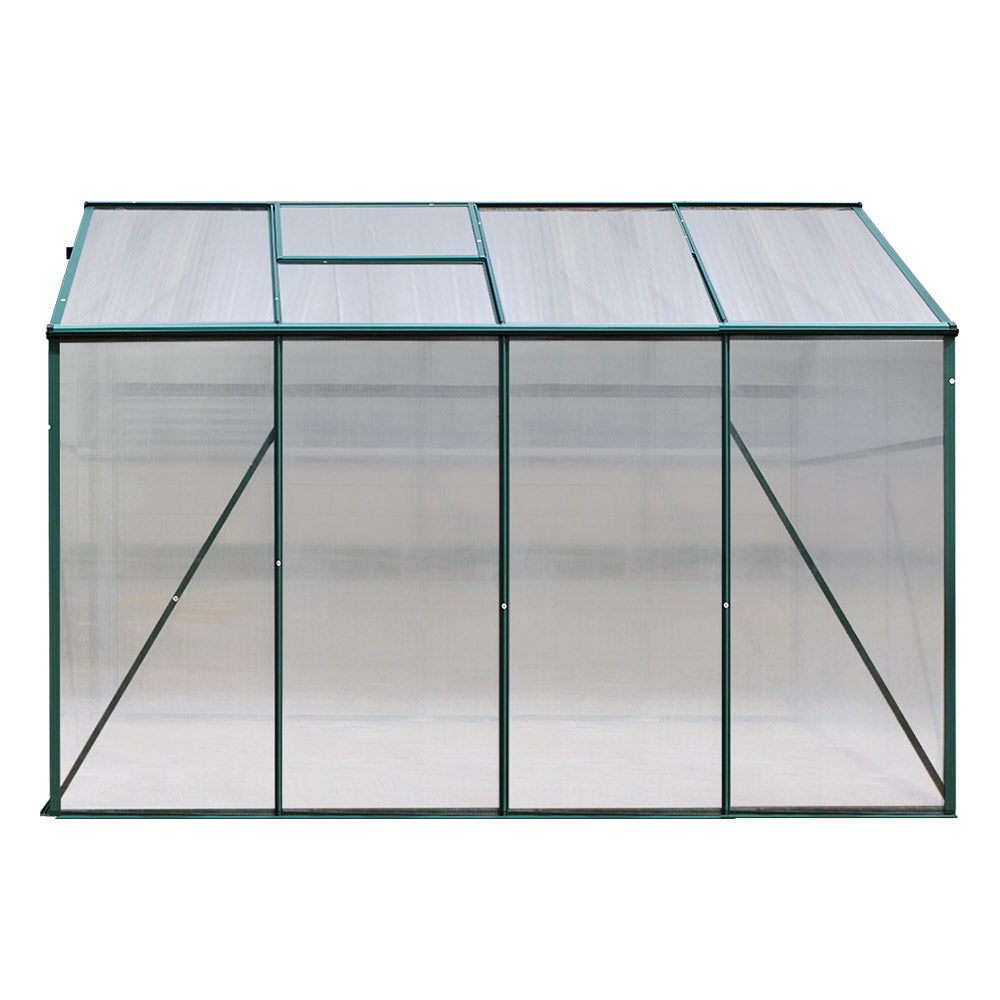 A rear view of the greenhouse, showing its rectangular structure with clear panels and a green frame.