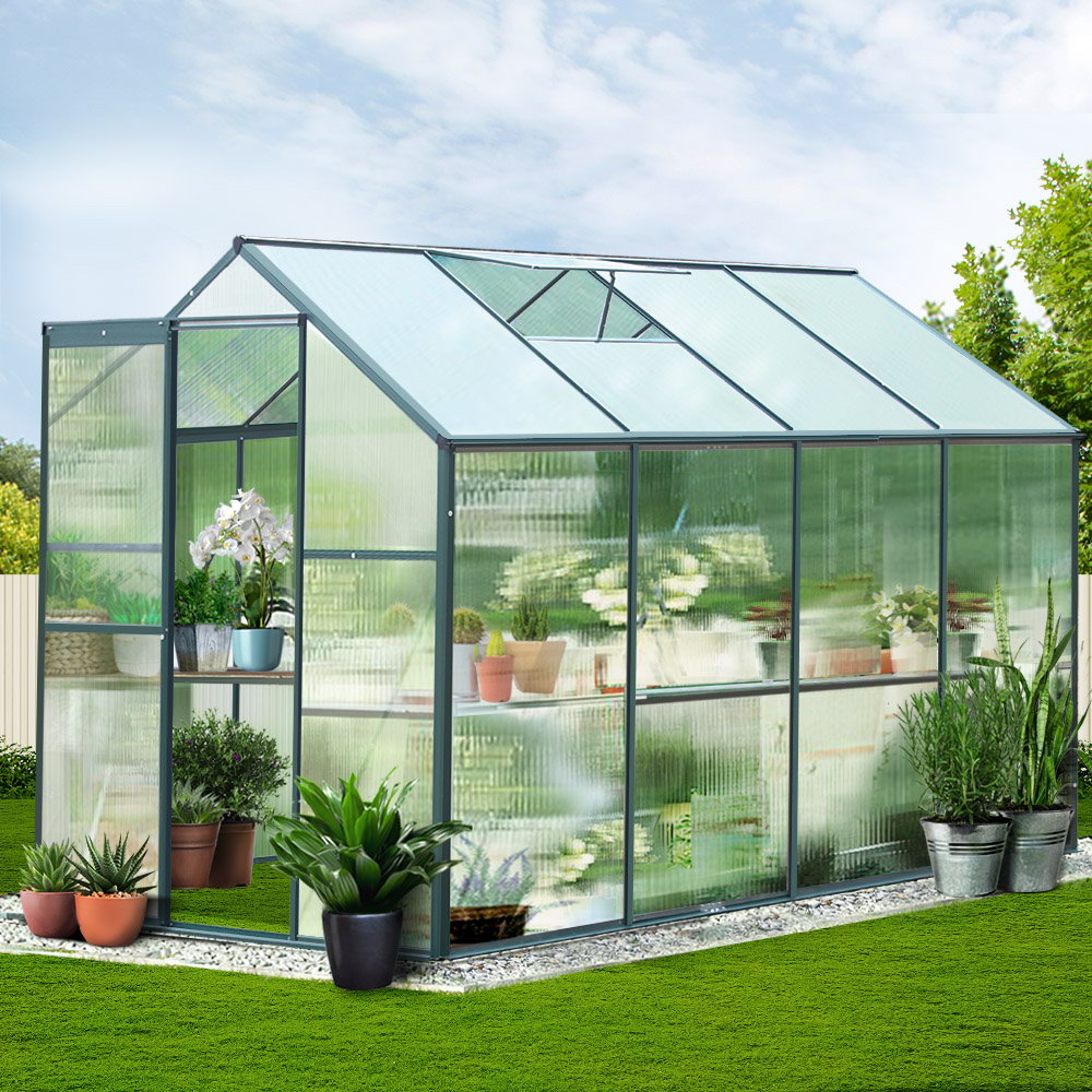 A real-life photo of a greenhouse placed in a garden setting, surrounded by lush greenery, showing its practical use.