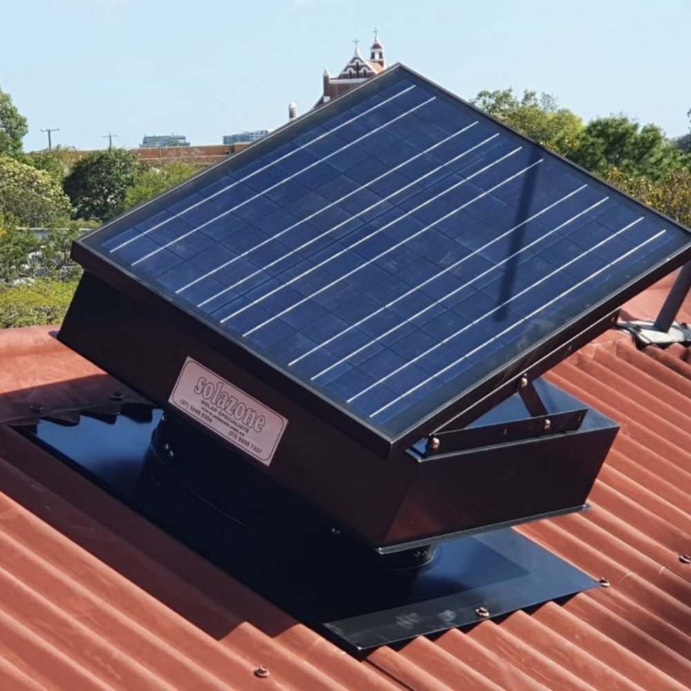 Black solar ventilator with an angled panel installed on a red metal roof under sunlight.