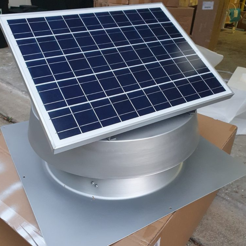 Tilted view of a silver ventilator with a small solar panel, placed on a wooden platform.