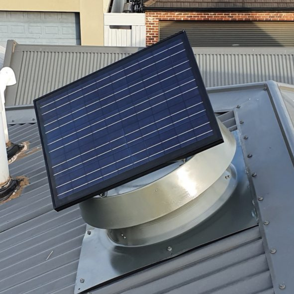 Silver ventilator with a large blue solar panel on a grey metal roof.