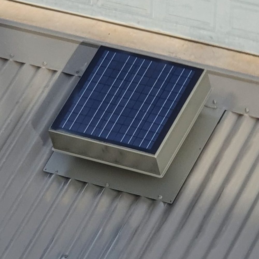 Rectangular solar roof ventilator positioned on a ribbed metal roof, panel tilted for maximum sunlight exposure.