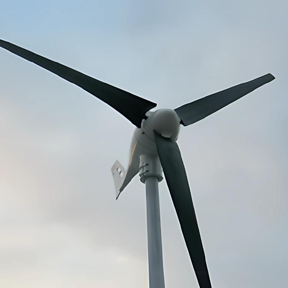 Wind turbine with black blades standing outdoors under a cloudy sky.