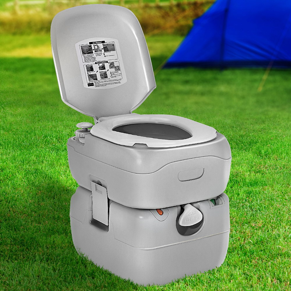 Camping toilet on grass near a tent, lid open, demonstrating outdoor use in a camping environment.