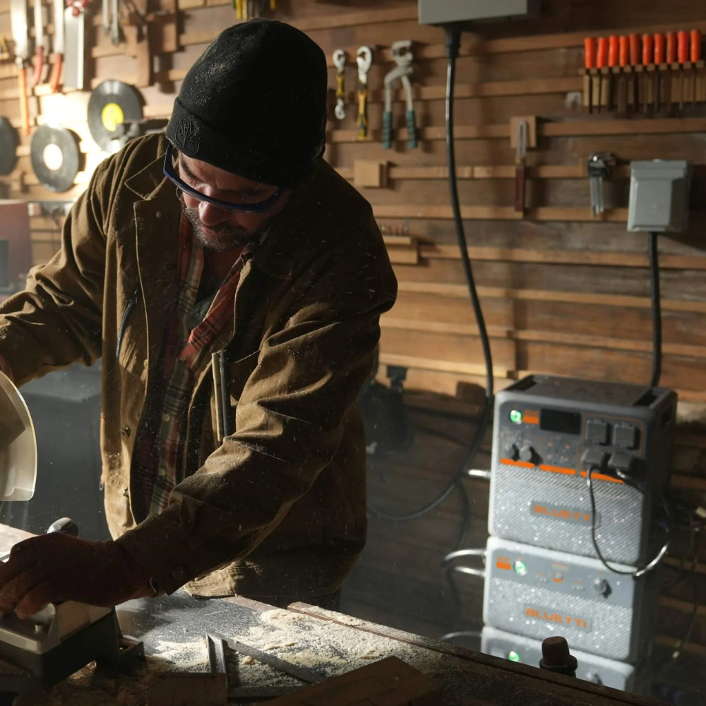 Person working indoors with Bluetti unit powering tools, illustrating rugged, off-grid worksite power supply.