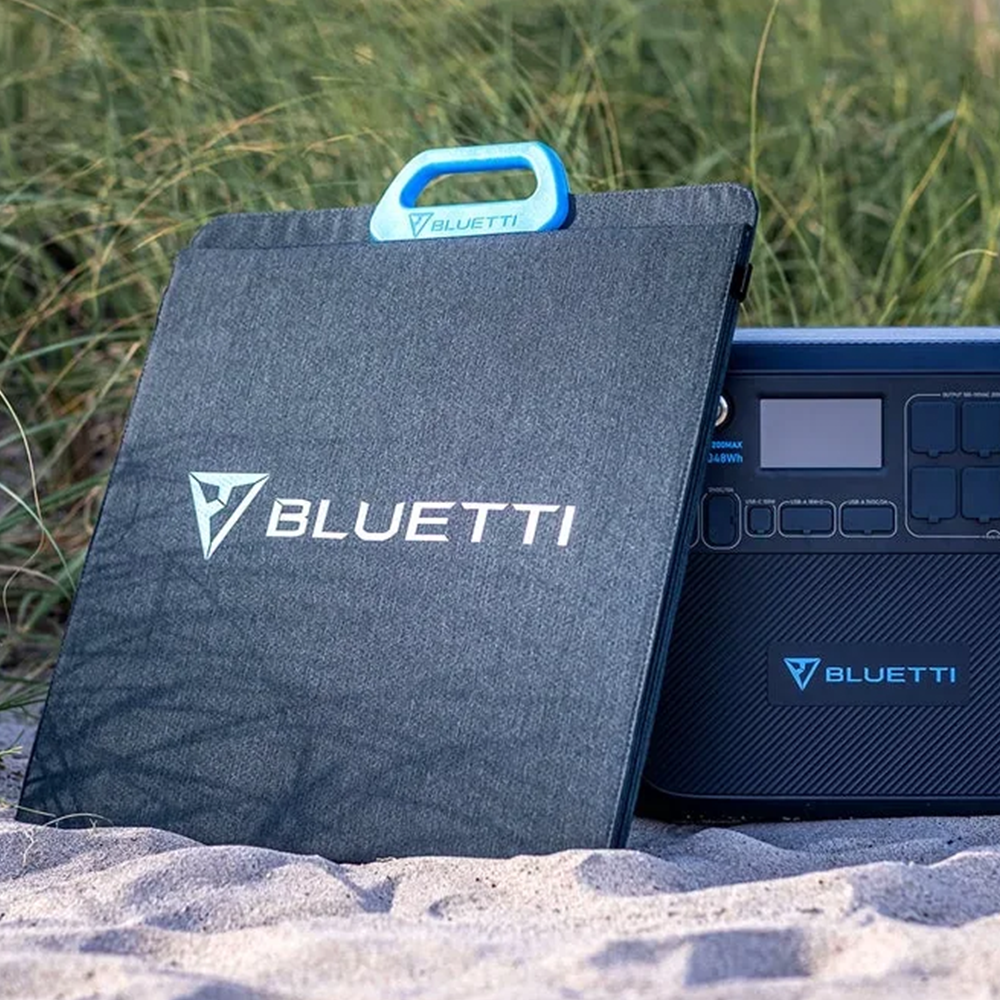 The BLUETTI solar panel sits next to the power station on the sand, encapsulating its durability and ability to perform in various environments