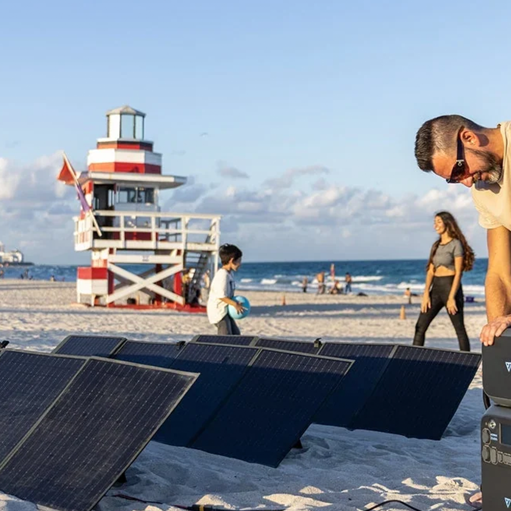 A family enjoys a sunny beach day with the BLUETTI solar panels charging on the sand, showing their high efficiency and suitability for coastal trips