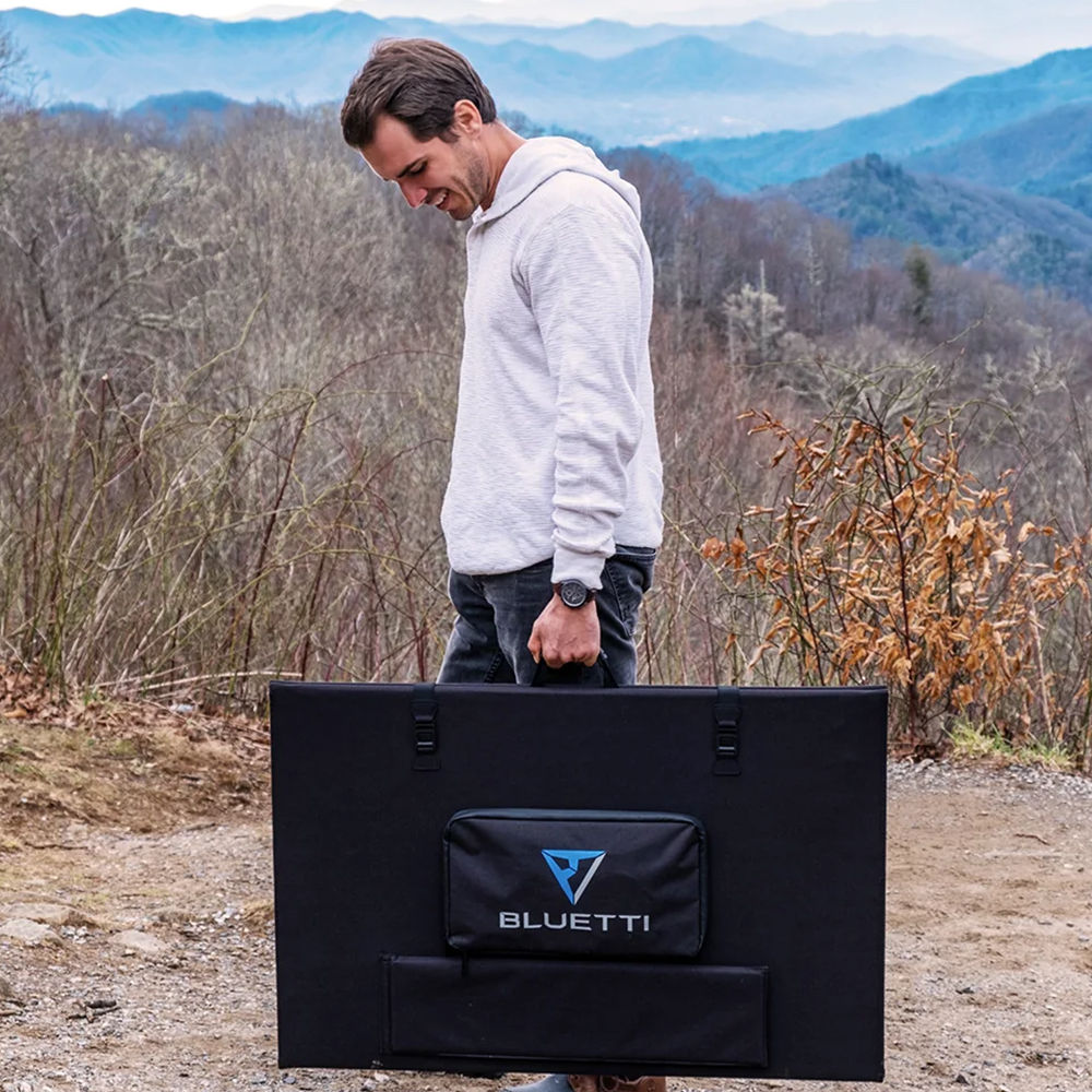 A person carrying the folded Bluetti solar panel by its handle, emphasizing the product's portability and lightweight design for outdoor enthusiasts