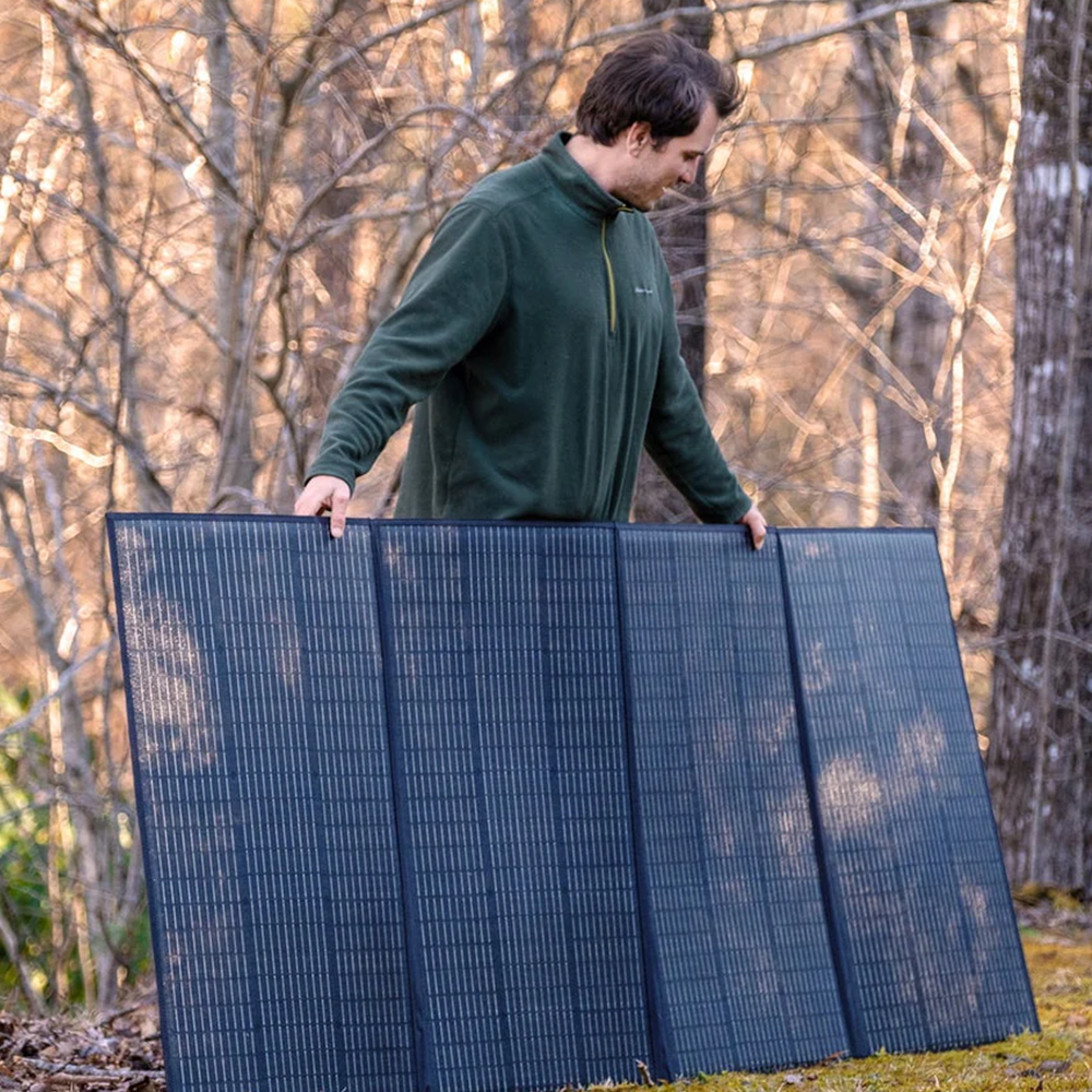 The Bluetti solar panel fully deployed in a forested area, with its black surface blending well with nature while efficiently capturing sunlight
