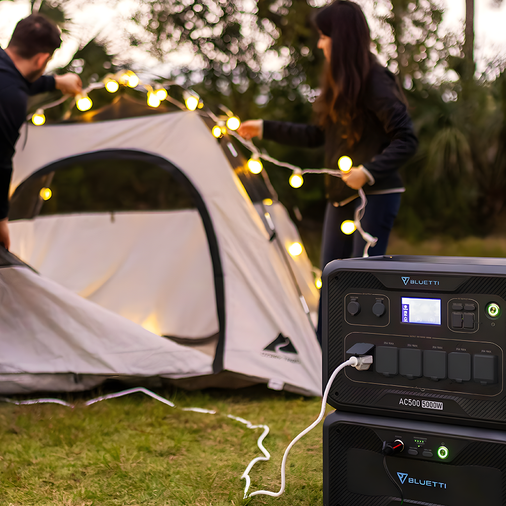 A lifestyle image featuring the power station in use at a campsite near a tent, providing electricity for outdoor activities.