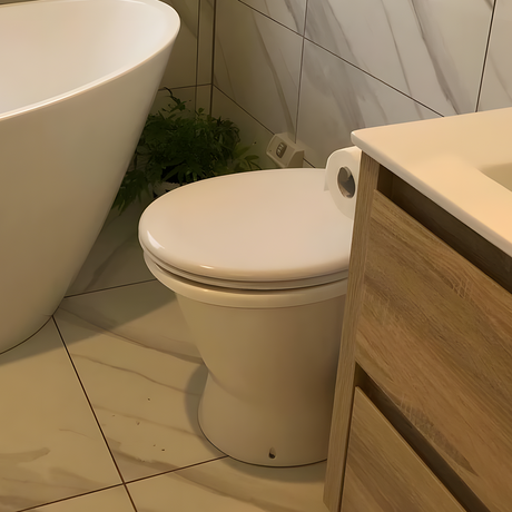 Modern bathroom with a white toilet next to a freestanding bathtub, featuring a soft-close toilet seat, natural wood cabinetry, and a potted plant for decor