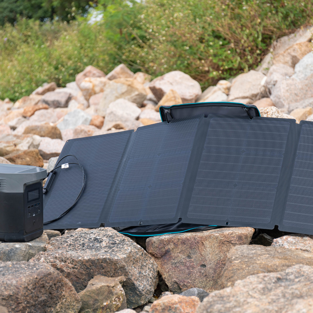 Foldable solar panel on rocks with a blurred natural background
