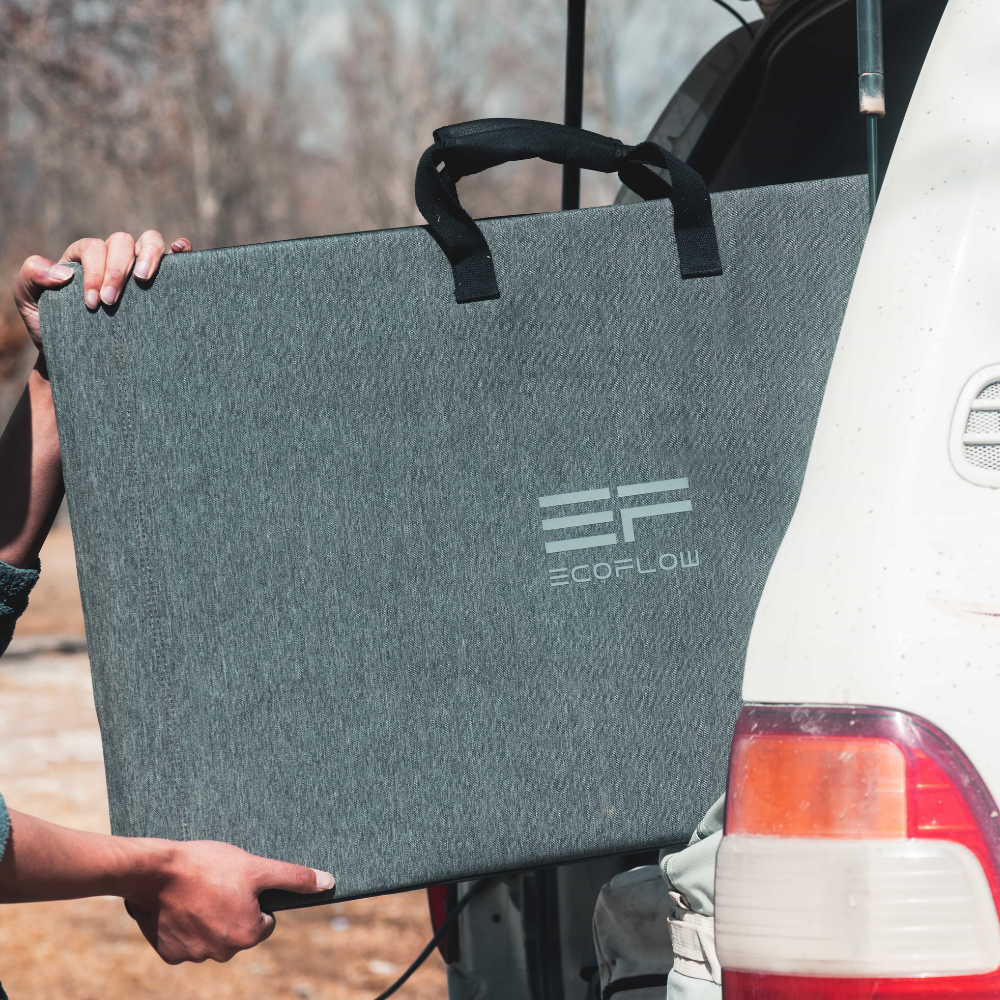 Person holding a gray EcoFlow product against a vehicle