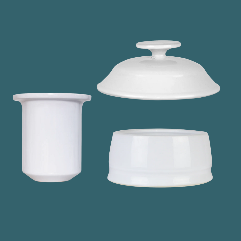 Three white ceramic containers with lids on a teal background