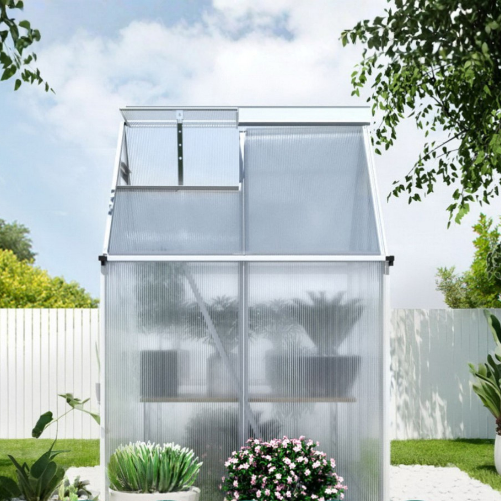 Small greenhouse with plants in a garden setting