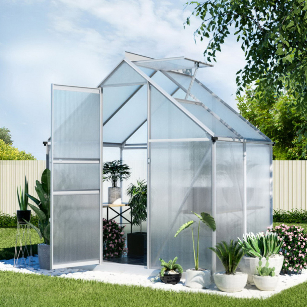 Clear glass greenhouse with plants in a garden setting