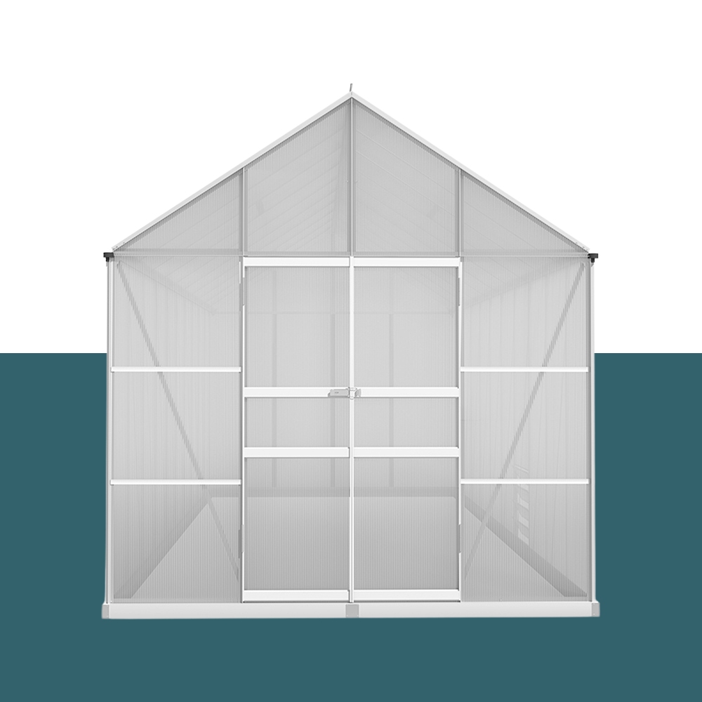 A front view of the large greenhouse with double doors in the centre and clear polycarbonate panel walls, supported by aluminium framing