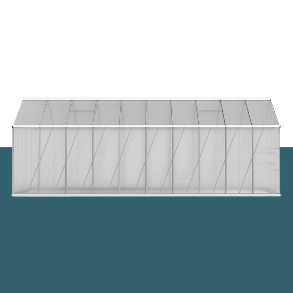 A side view of the greenhouse, highlighting the structure's length and the sloped roof made from polycarbonate panels supported by aluminium frames