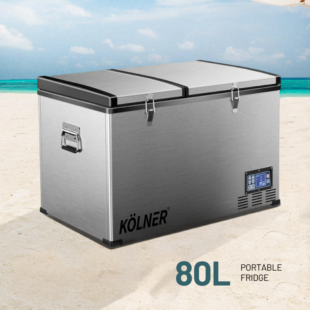 Kölner 80L portable fridge on a beach with turquoise water and blue sky.
