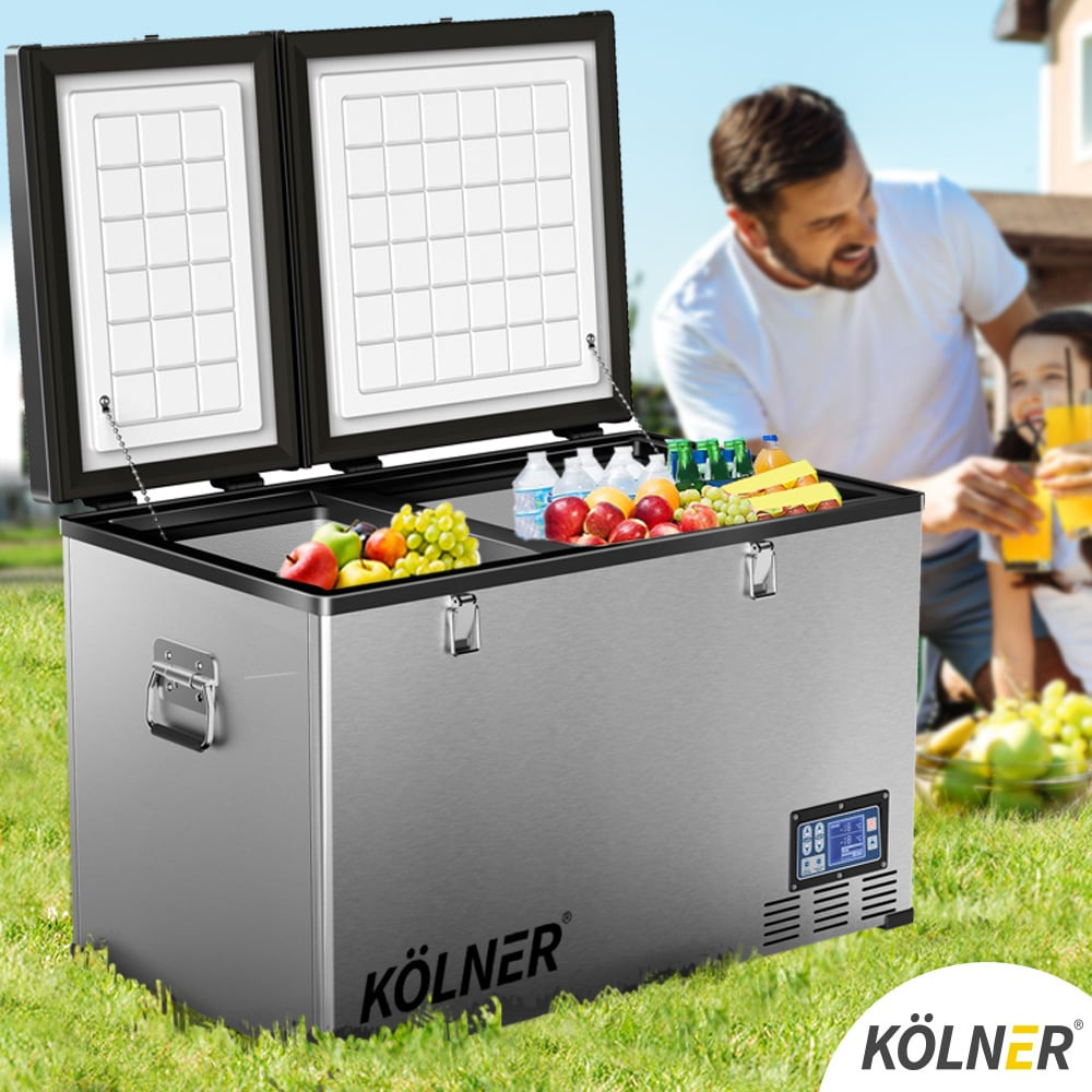 Kölner portable refrigerator with food items on a grassy area, with a man and child in the background.