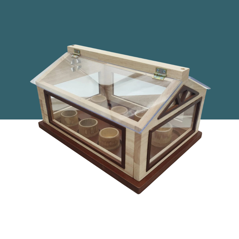 Mini Greenhouse Display
A wooden and glass mini greenhouse with a pitched roof, featuring small brown plant pots inside, sitting on a dark wooden base.