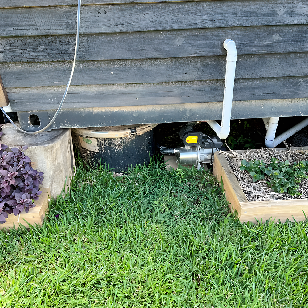 Composting toilet installed outdoors – A Nature Loo Alectura composting toilet system set up outside a wooden structure with a drainage system.