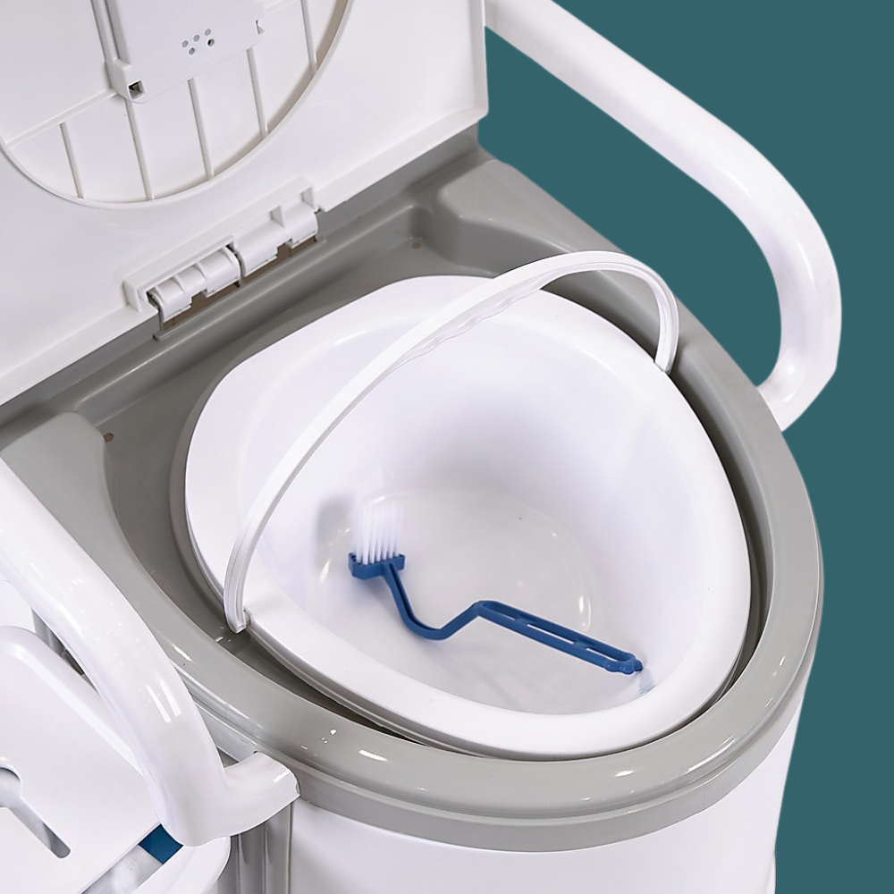 A high-angle view looking down into the toilet with the seat lid raised. It reveals the removable inner white bucket. A blue cleaning brush is resting inside the bucket.