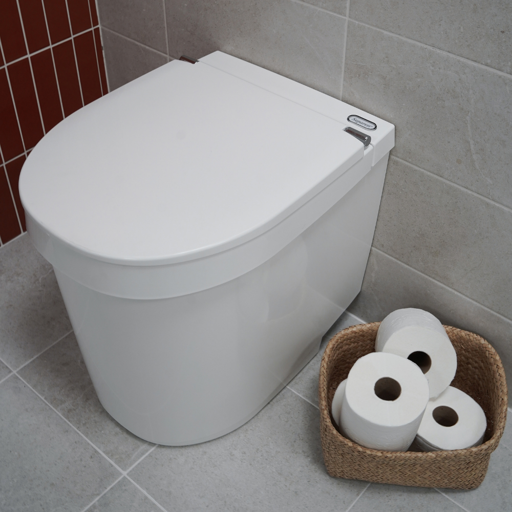 White toilet with a basket of toilet paper on a tiled bathroom floor