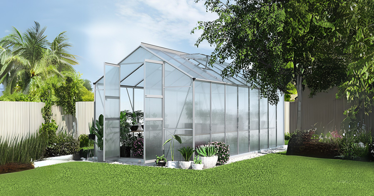 A close-up of ripe red tomatoes growing inside a greenhouse, with vibrant green leaves in the background. Caption: Choose Plants to Suit Your Greenhouse.