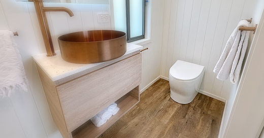 A clean, modern composting toilet setup, featuring a wooden toilet seat in a bright, minimalistic bathroom. This image emphasizes the aesthetic appeal of well-maintained systems.