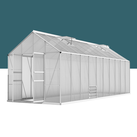 A long, white-framed greenhouse with a gabled roof, translucent panels, roof vents, and a sliding door.