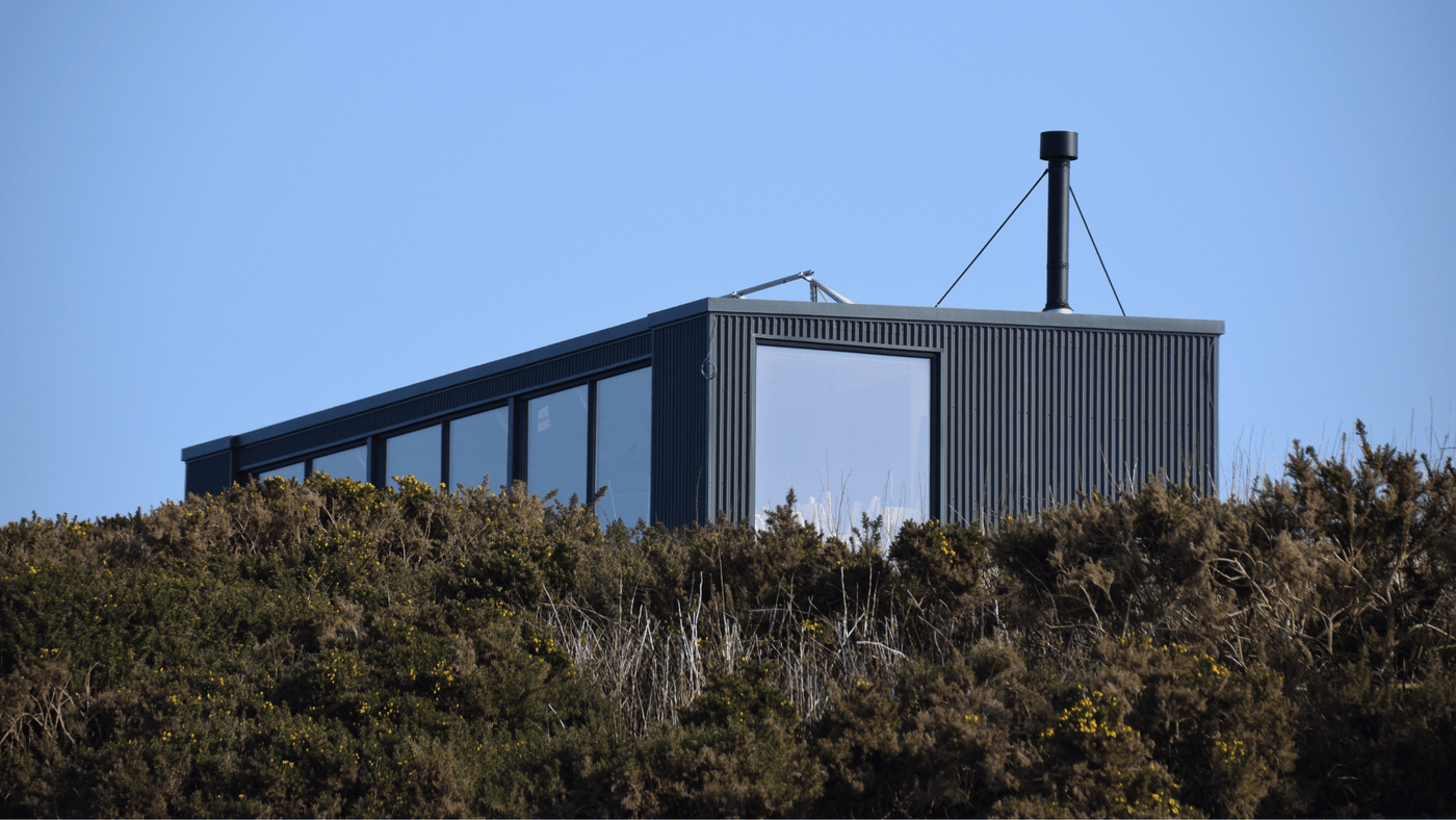 off grid home set amongst shrubs against a blue sky