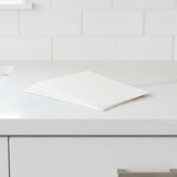 Stack of Separett Tiny® absorb pads placed on a white countertop with tiled background.