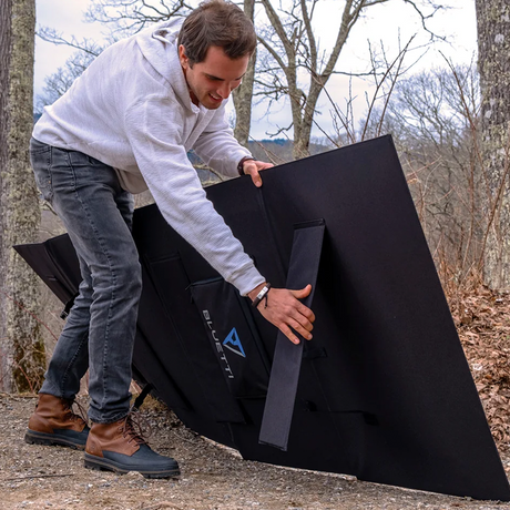 An individual unfolding the solar panel and setting up the kickstand, demonstrating the user-friendly setup process and durable hinge mechanism