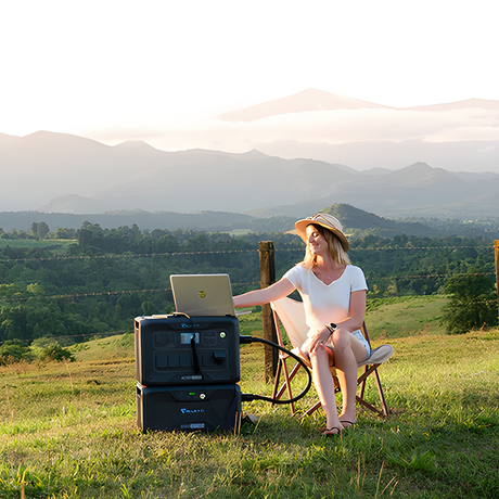 A power station powering appliances in an open field, with a person enjoying the view in a serene outdoor setting.