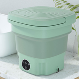 Green kitchen compost bin on a white surface with a plant in the background