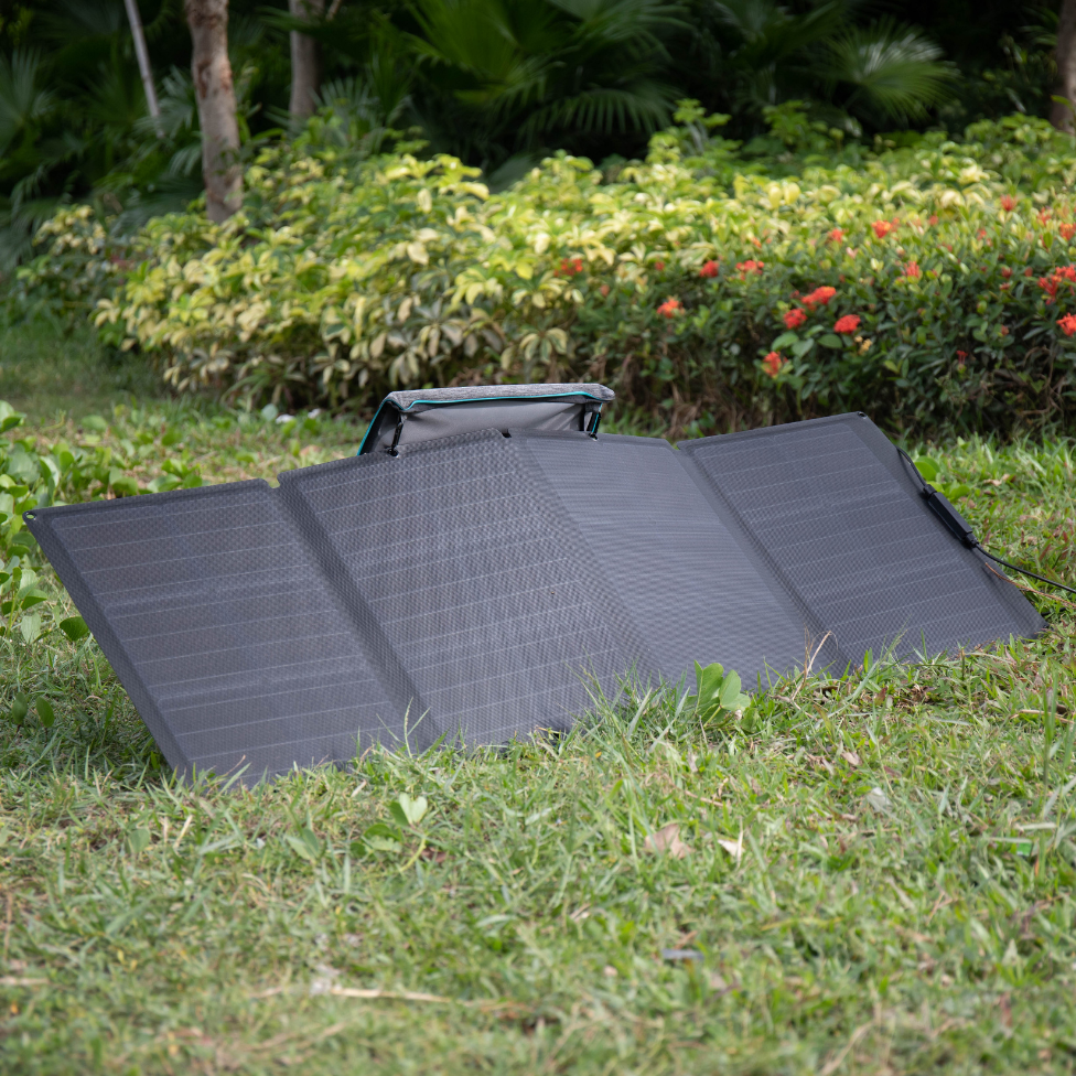 Foldable solar panel on grass with greenery in the background