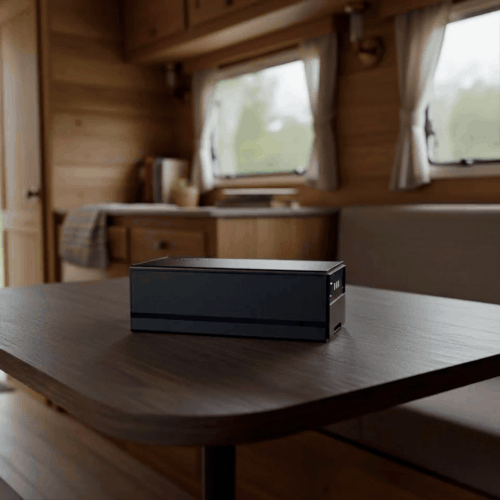 Compact 298Wh Glacier Plug‑in Battery on a wooden table with a blurred background of a cabin interior.