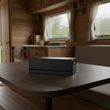 Compact 298Wh Glacier Plug‑in Battery on a wooden table with a blurred background of a cabin interior.