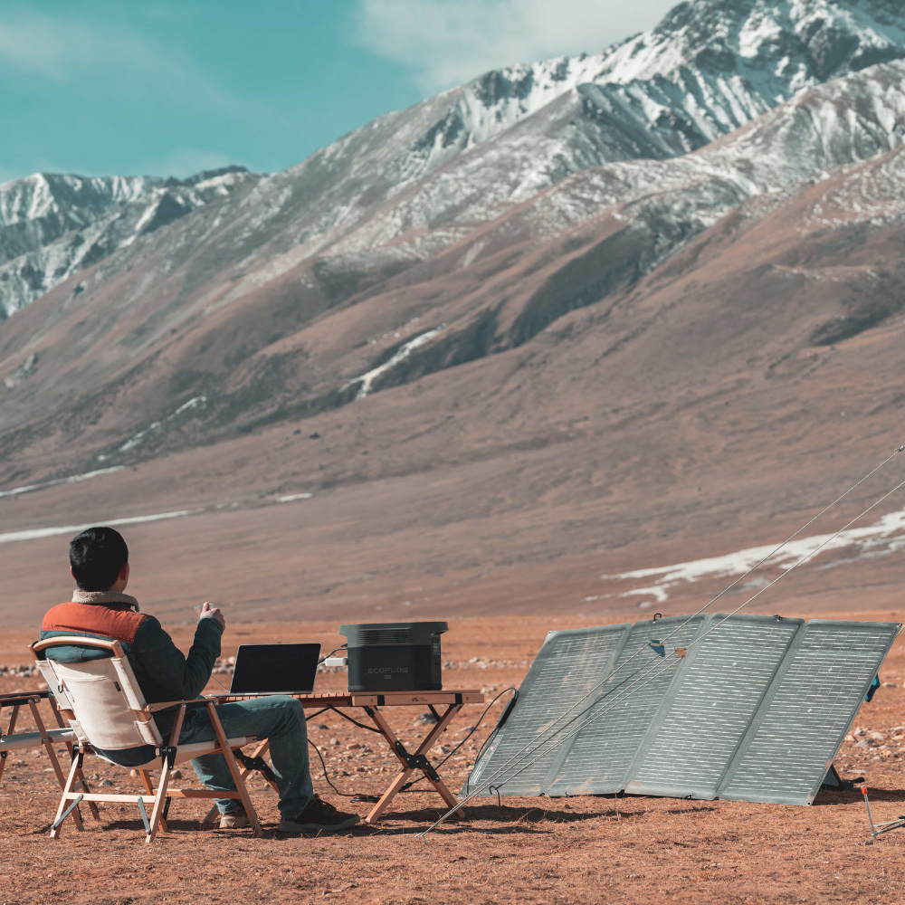 Person sitting in a chair with a laptop in front of a scenic mountain landscape