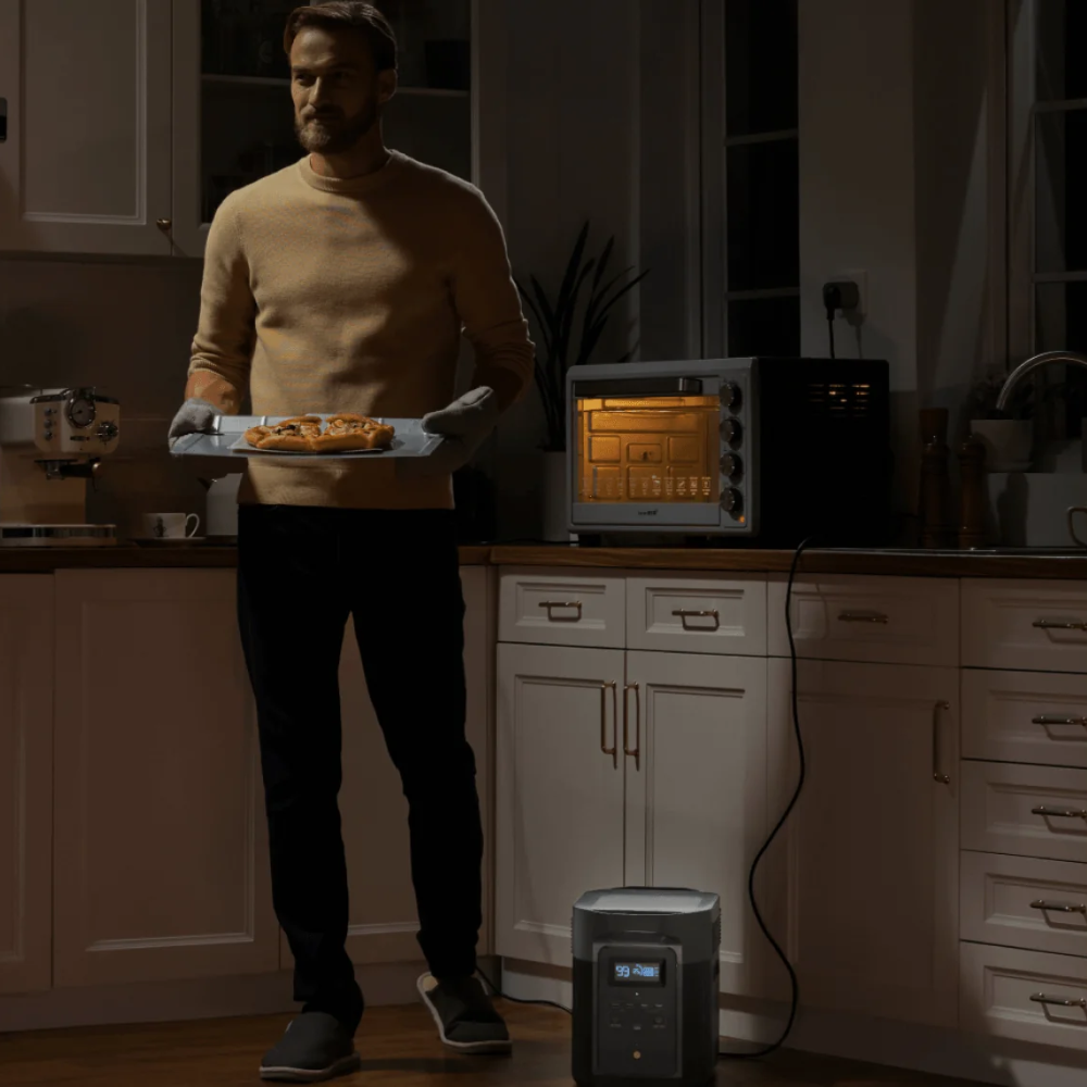 Man holding a plate of food in a kitchen with a dehumidifier on the floor.