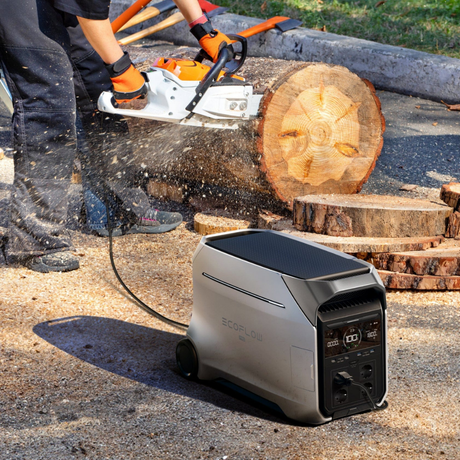 Person using a chainsaw to cut a log with a power station nearby