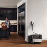 Person in a kitchen with a portable power station plugged into an outlet.