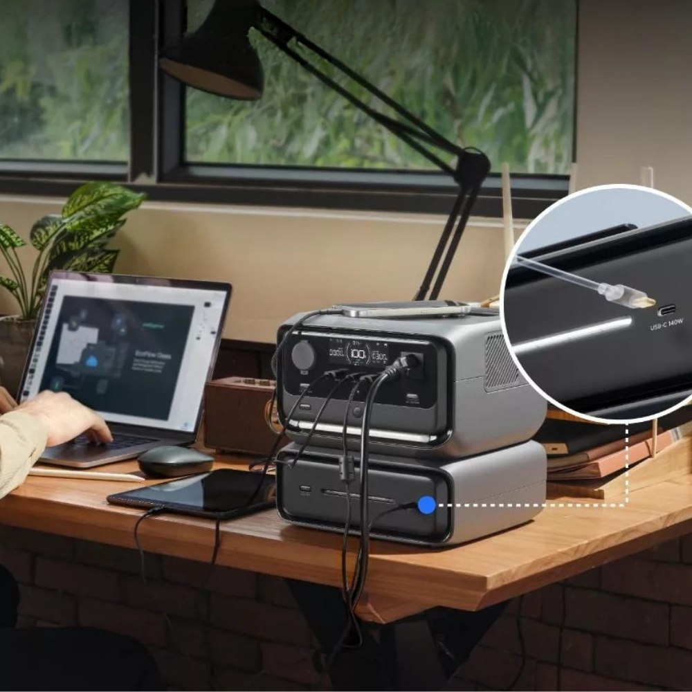 Desk setup with a power station, laptop, and phone, featuring an inset of a cable connection.