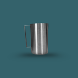 Stainless steel pitcher on a teal background