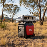 Red and black generator in a field with a camper on top