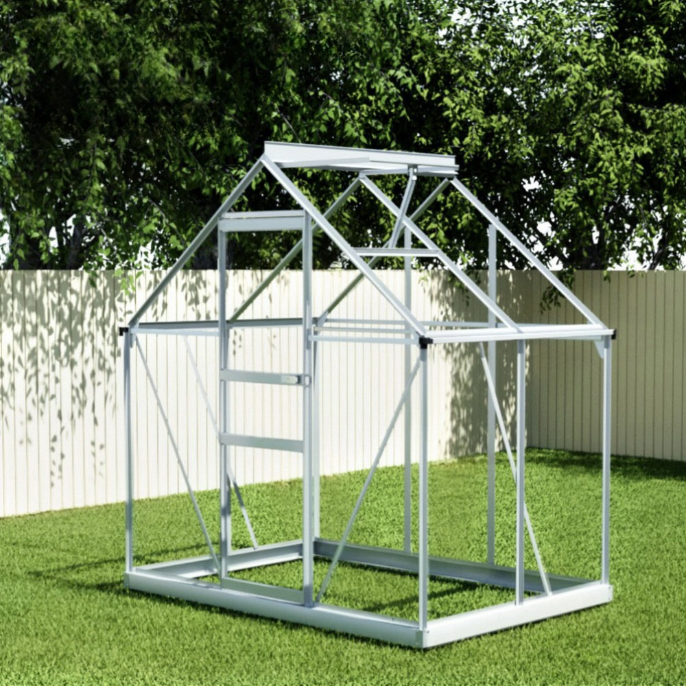 Metal greenhouse frame on grass with trees in the background