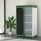 A Green Fingers hydroponic grow tent with black and neon green trim features shelving and sits next to a potted plant.