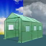 Green portable greenhouse with windows against a blue sky and clouds background